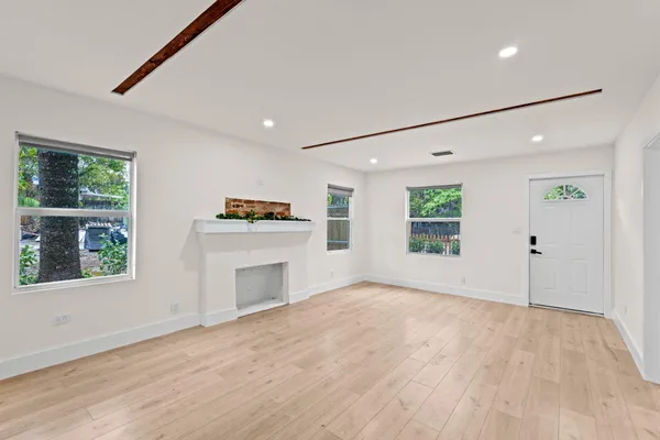 an empty room with windows and fireplace
