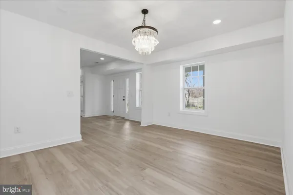 an empty room with wooden floor a refrigerator and windows