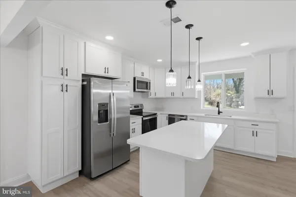 a kitchen with kitchen island a sink stainless steel appliances and white cabinets