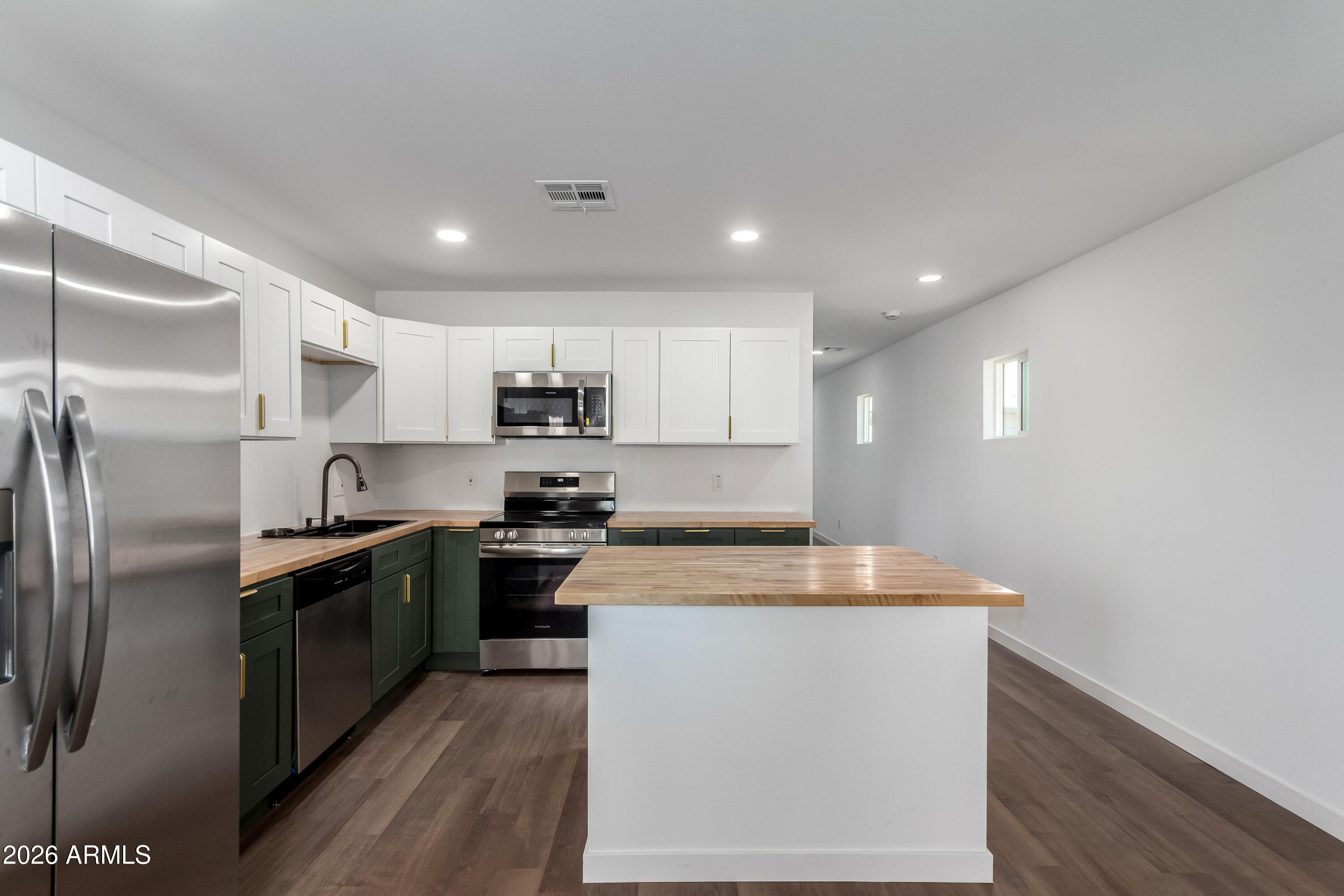 9155 West Adams Street Tolleson, AZ 85353 - Photo 7 of 29 a kitchen with stainless steel appliances granite countertop a refrigerator a sink dishwasher a stove and white countertops with wooden floor