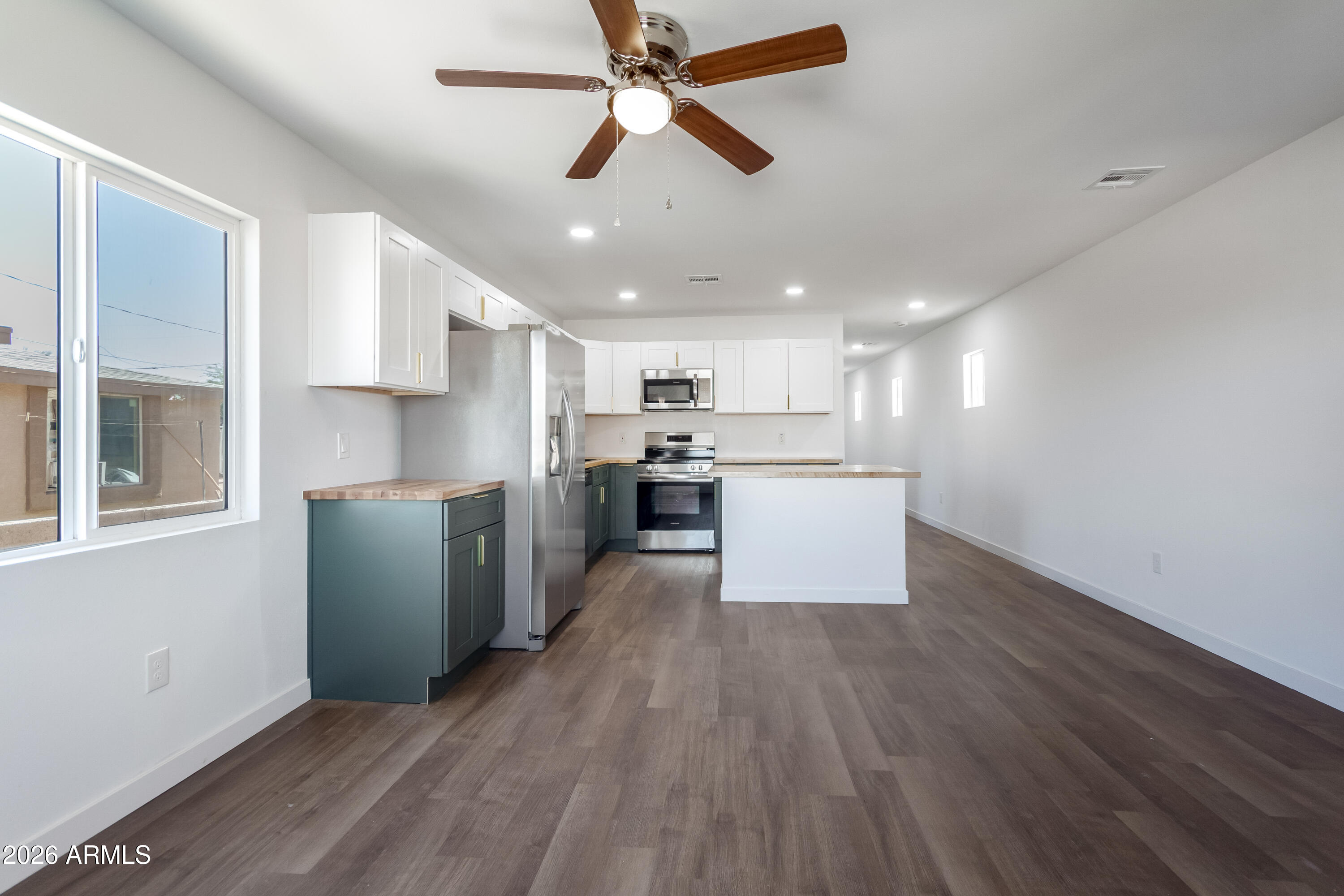 9155 West Adams Street Tolleson, AZ 85353 - Photo 9 of 29 a kitchen with kitchen island white cabinets and stainless steel appliances