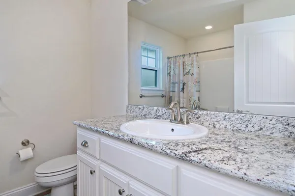 a bathroom with a granite countertop sink a toilet and a mirror