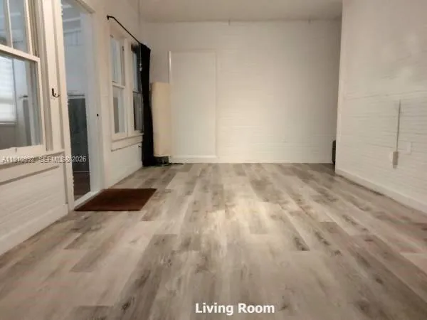 a view of a room with wooden floor and a white door