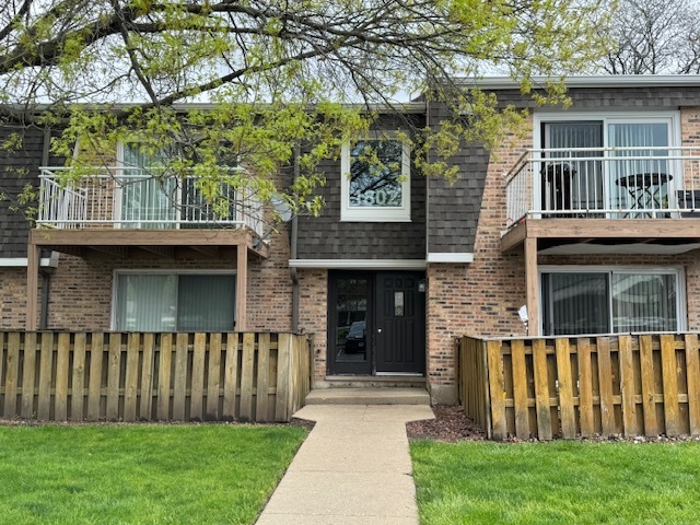 1802 Plum Grove Road, Unit 1D Rolling Meadows, IL 60008 - Photo 1 of 14 a front view of a house with a garden