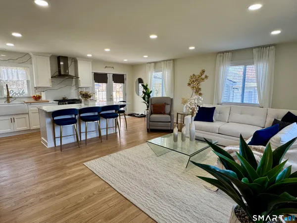 a living room with furniture a wooden floor and kitchen view