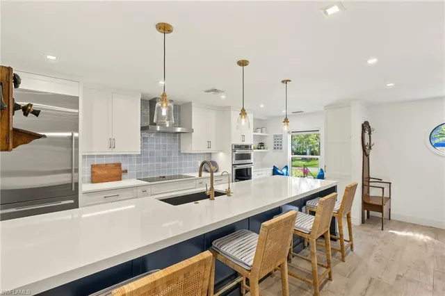 a kitchen with stainless steel appliances a dining table chairs and white cabinets next to a window
