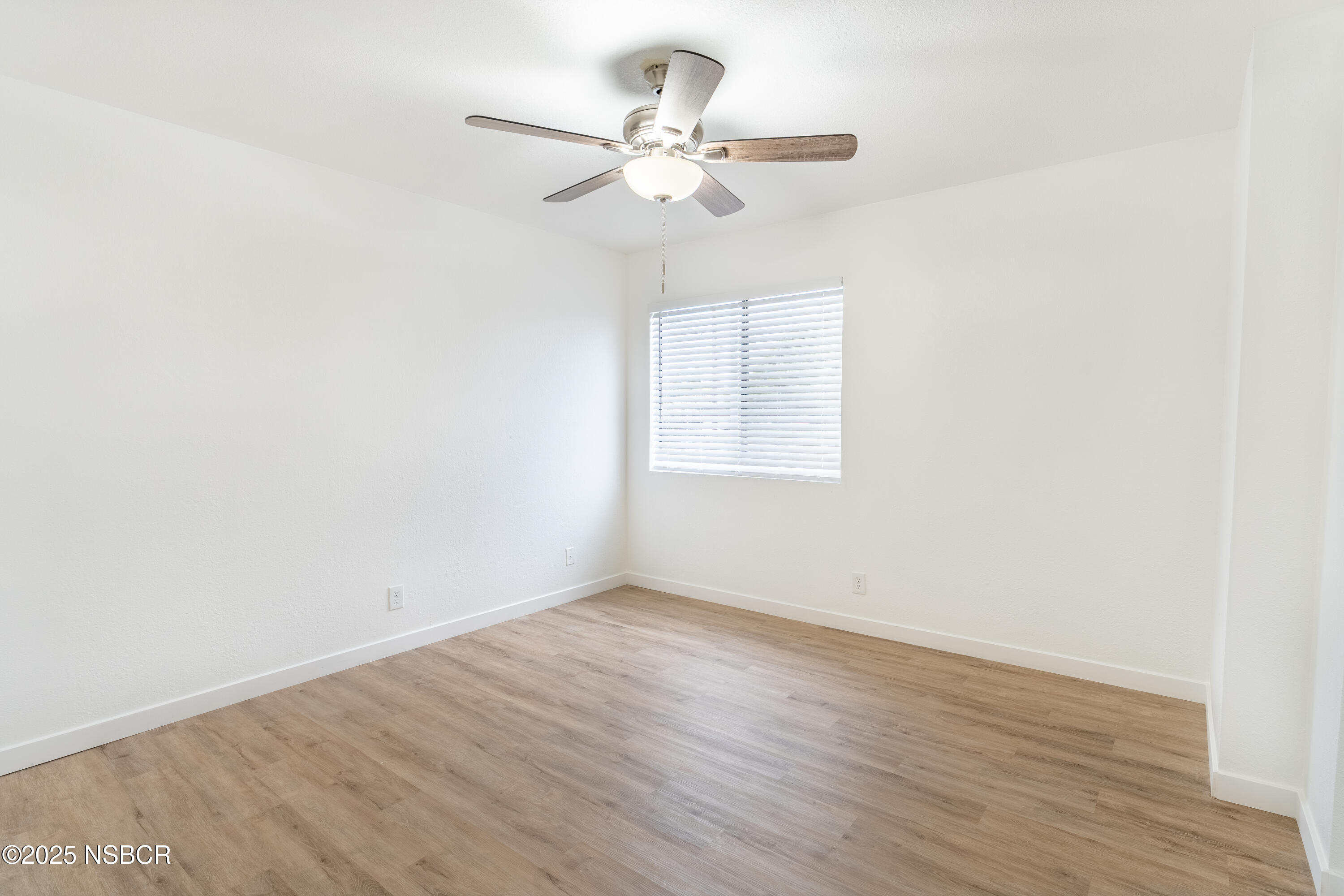 1200 East Walnut Avenue, Unit A Lompoc, CA 93436 - Photo 11 of 23 an empty room with wooden floor fan and windows
