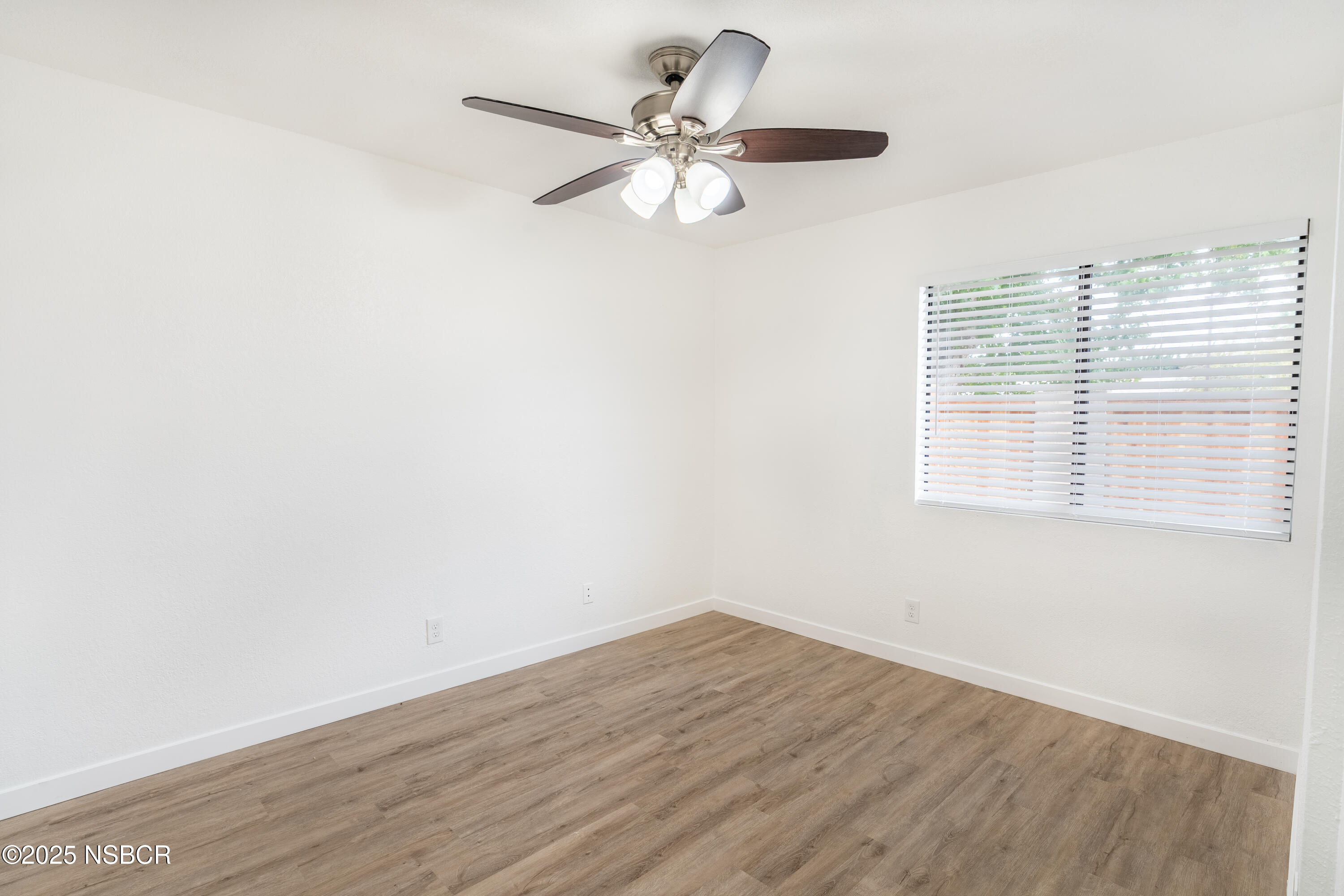 1200 East Walnut Avenue, Unit A Lompoc, CA 93436 - Photo 13 of 23 an empty room with wooden floor fan and windows