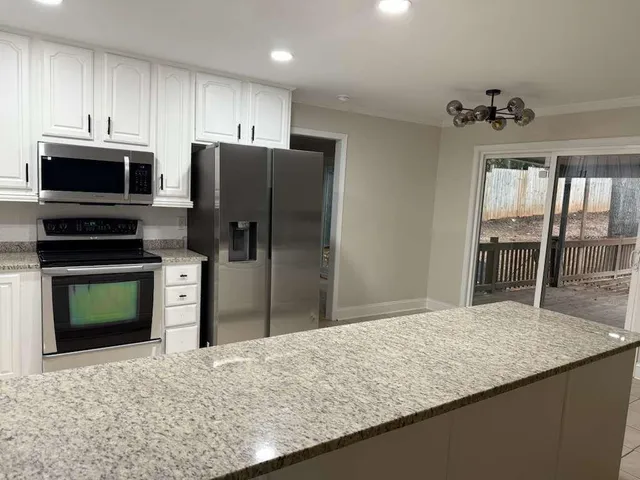 a kitchen with stainless steel appliances granite countertop a refrigerator a stove and a sink