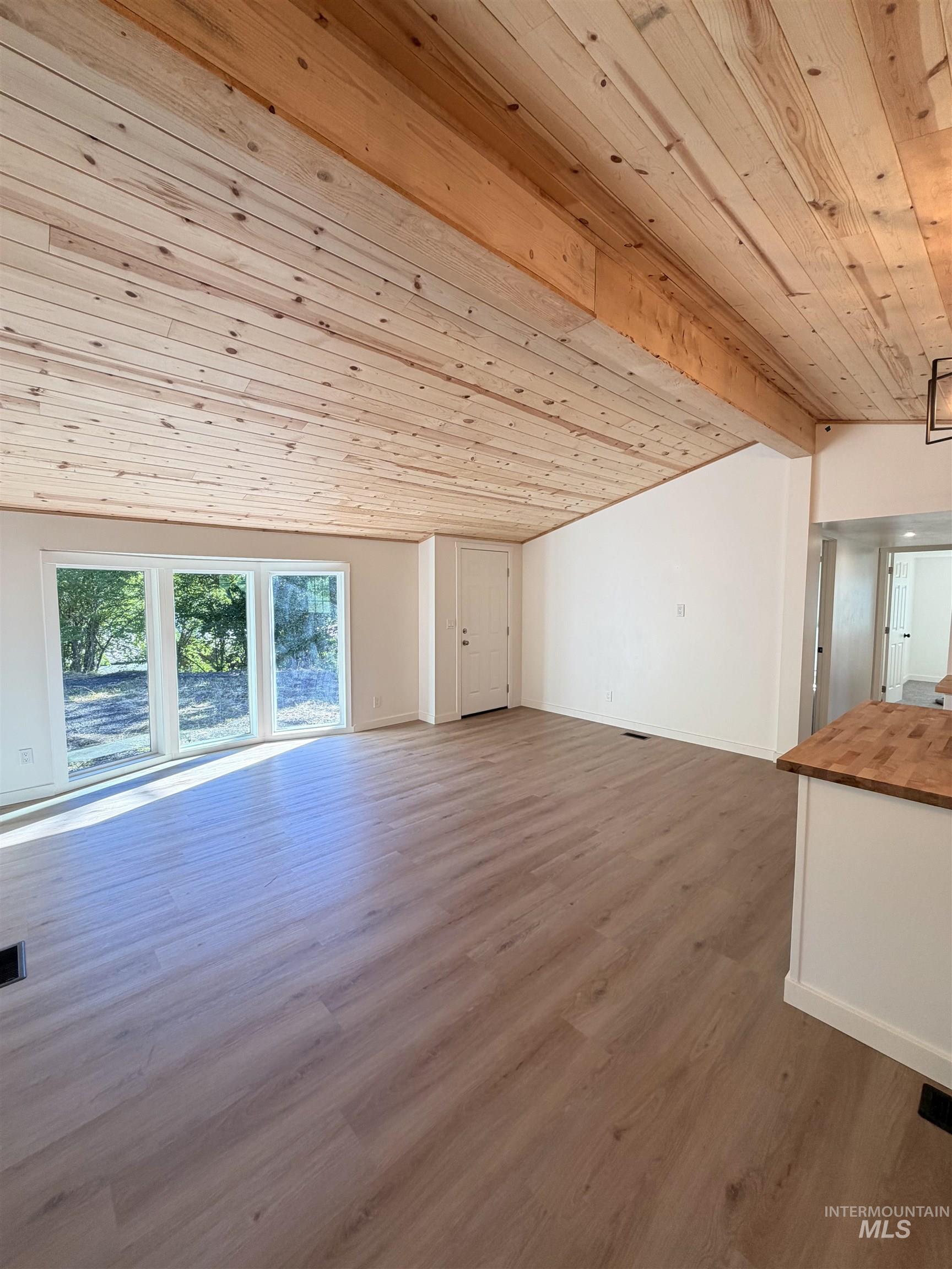 151 View Road Kamiah, ID 83536 - Photo 16 of 49 Spacious living area featuring a vaulted wood-plank ceiling with exposed beams, wood-finish flooring, a white countertop, and multiple sliding glass doors