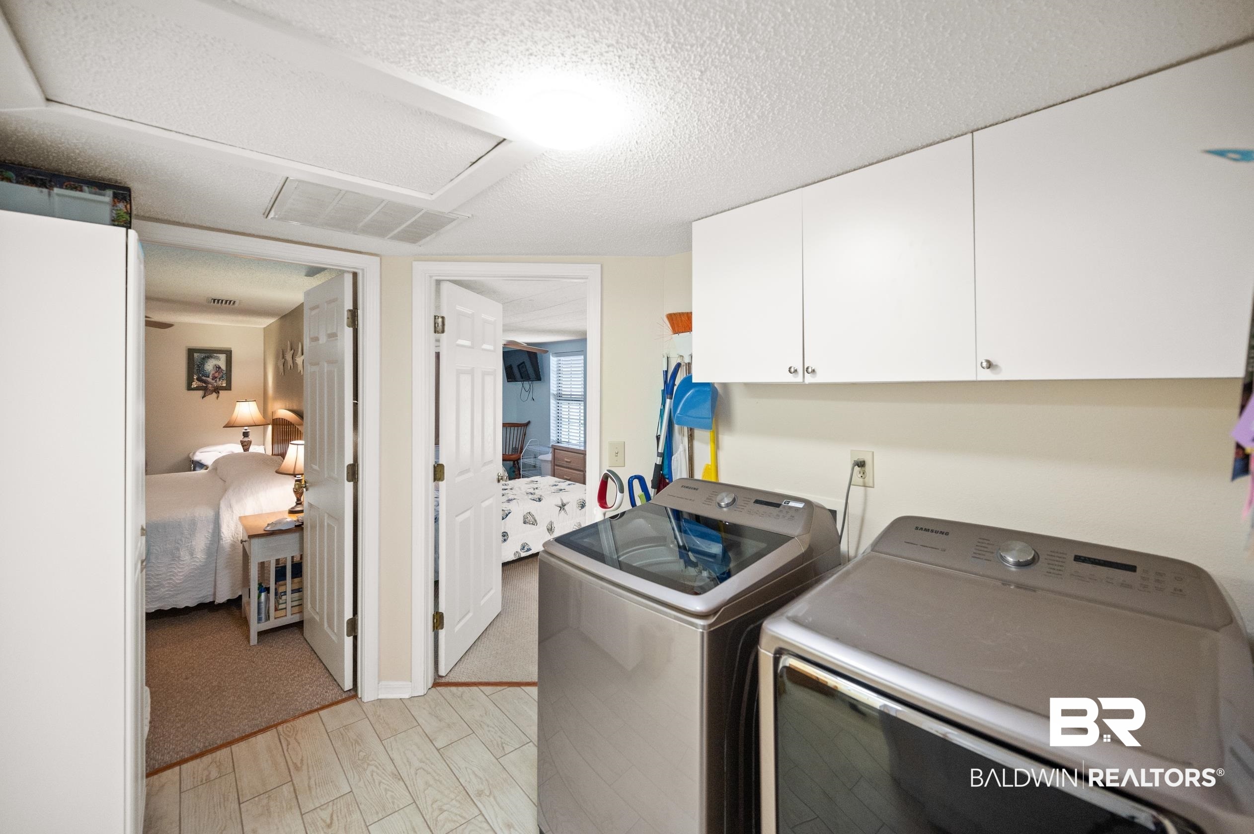 5392 Ornacor Avenue Orange Beach, AL 36561 - Photo 25 of 48 Laundry area featuring washer and dryer, light colored carpet, a textured ceiling, and cabinets
