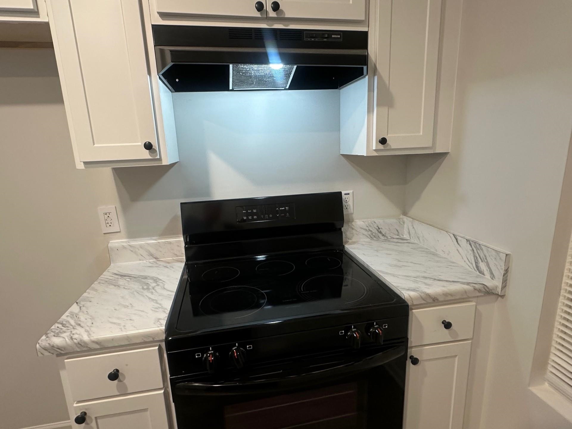 2585 Callie Road Memphis, TN 38127 - Photo 6 of 13 Kitchen with under cabinet range hood, white cabinetry, and black range with electric stovetop