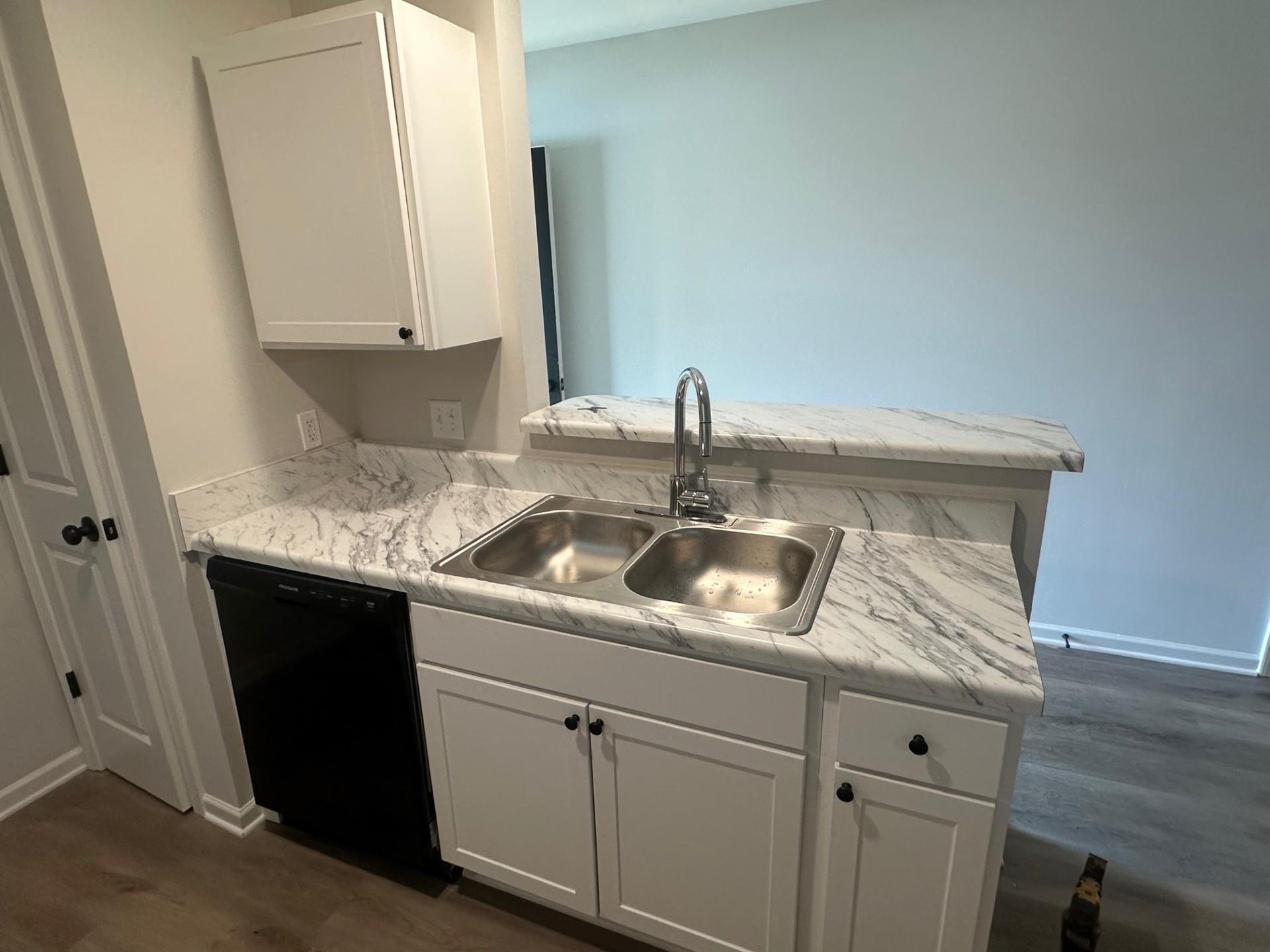 2585 Callie Road Memphis, TN 38127 - Photo 8 of 13 Kitchen featuring white cabinets, light countertops, a sink, baseboards, and black dishwasher