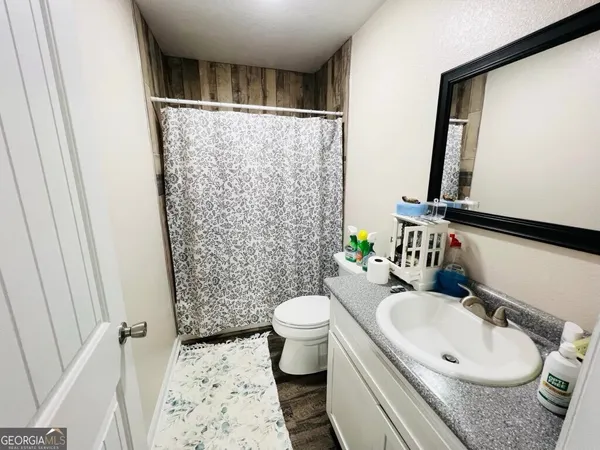 a bathroom with a sink a toilet a mirror and shower curtain