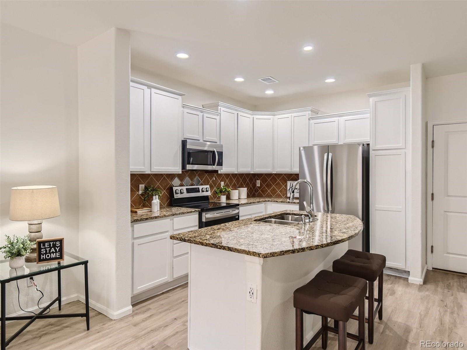 8935 East Nichols Place Centennial, CO 80112 - Photo 1 of 24 a kitchen with a refrigerator a stove a sink a dining table and chairs
