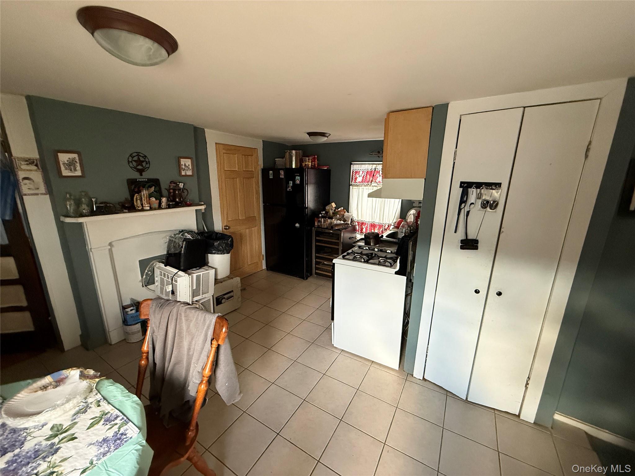 101 North Clinton Street Poughkeepsie, NY 12601 - Photo 5 of 11 Kitchen featuring freestanding refrigerator, white range with gas cooktop, light tile patterned flooring, and under cabinet range hood