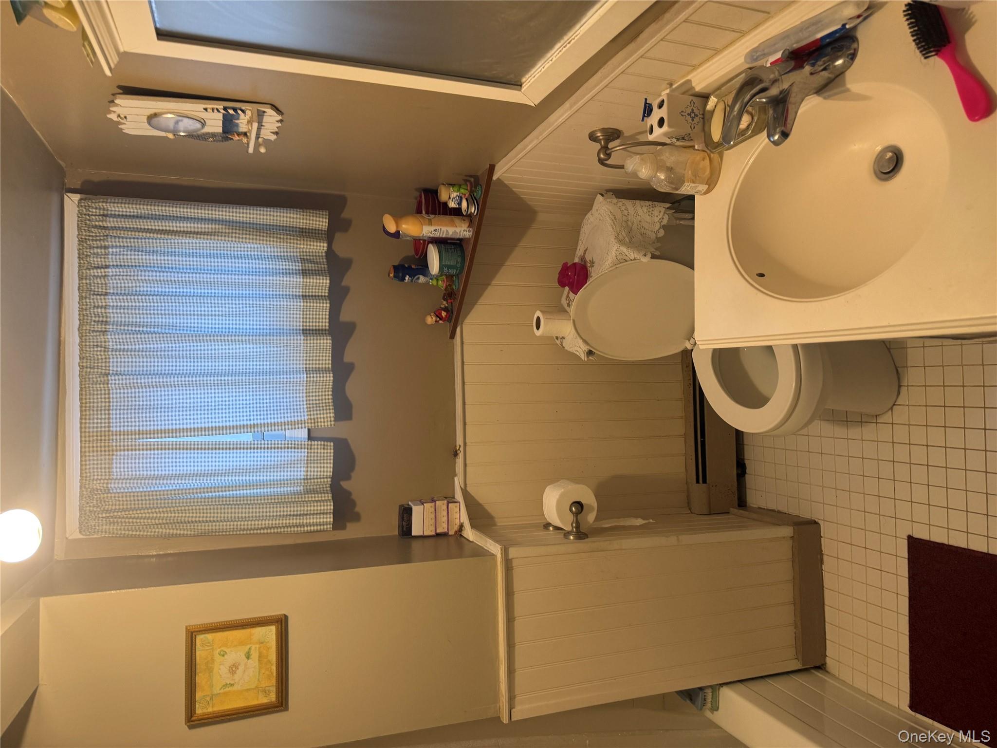 101 North Clinton Street Poughkeepsie, NY 12601 - Photo 10 of 11 Bathroom featuring wainscoting, vanity, a baseboard radiator, light tile patterned floors, and a decorative wall