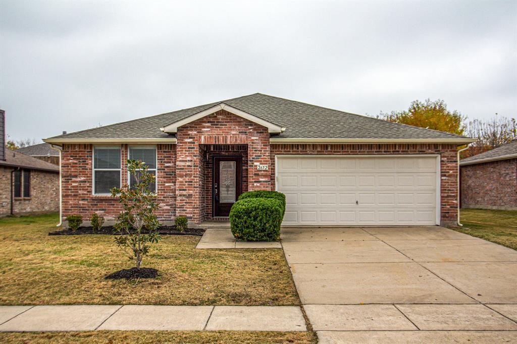 Ranch-style house with roof with shingles, brick siding, driveway, and a front lawn