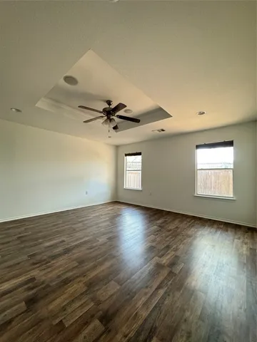 an empty room with wooden floor fan and windows