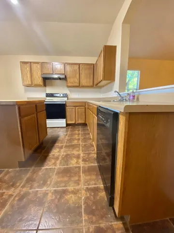 a kitchen with stainless steel appliances a sink a stove top oven a counter space and cabinets