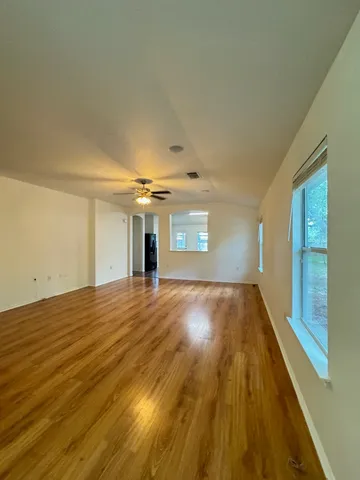 a view of empty room with wooden floor and fan
