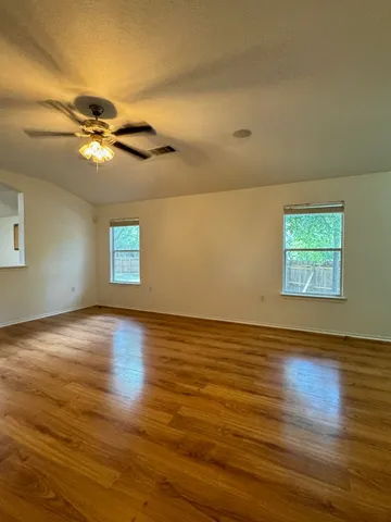 a view of an empty room with wooden floor and a window