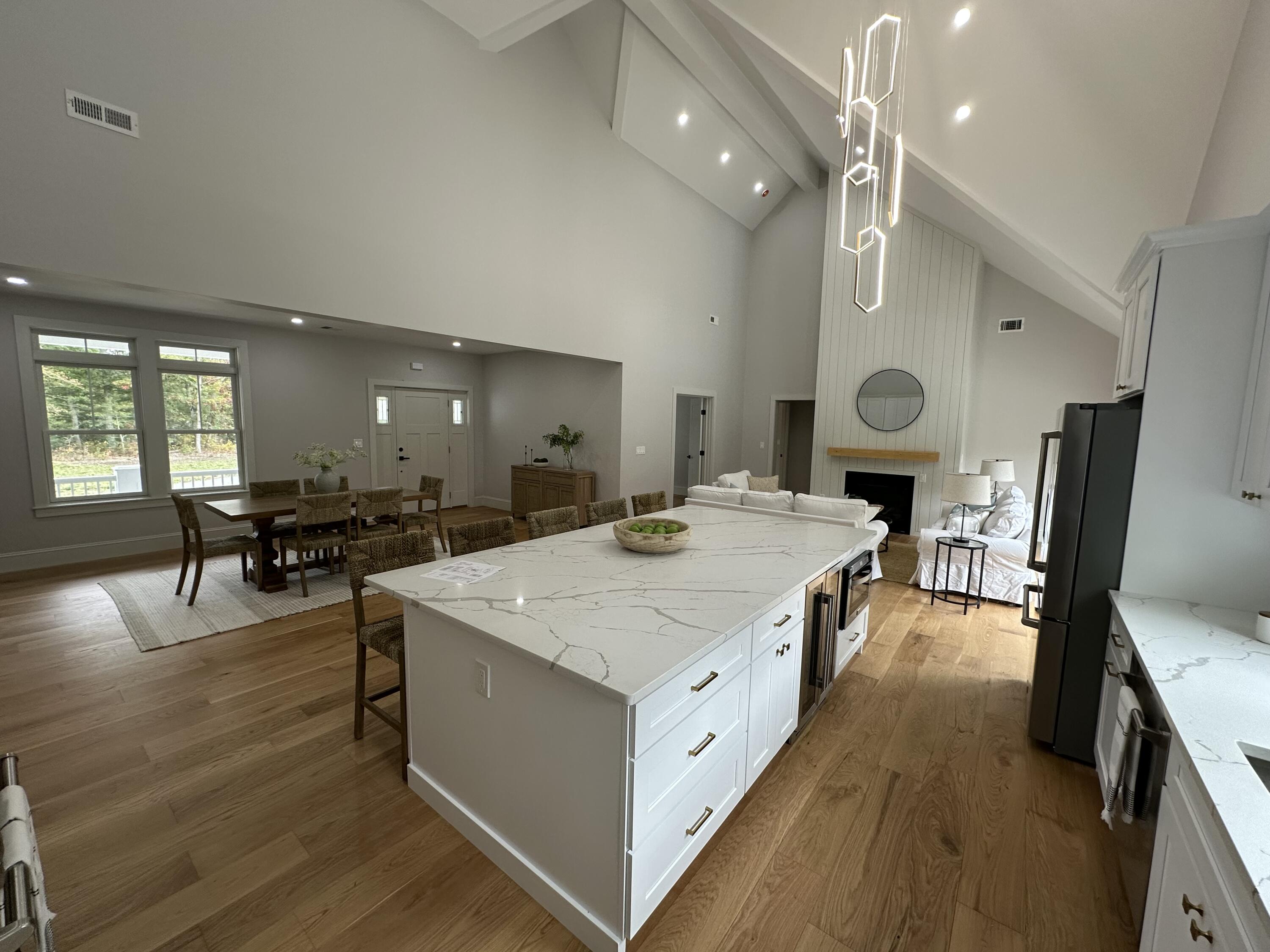 84 Hooppole Road Mashpee, MA 02649 - Photo 12 of 54 a large kitchen with kitchen island a stove a sink a dining table and chairs with wooden floor