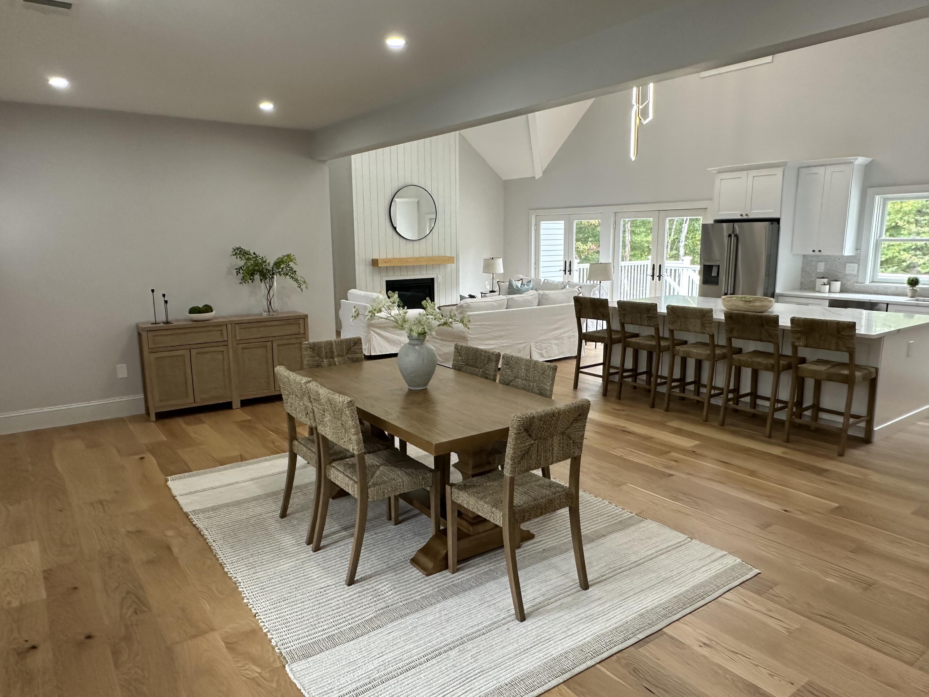 84 Hooppole Road Mashpee, MA 02649 - Photo 10 of 54 a view of a dining room and livingroom with furniture wooden floor a rug a fireplace and a chandelier