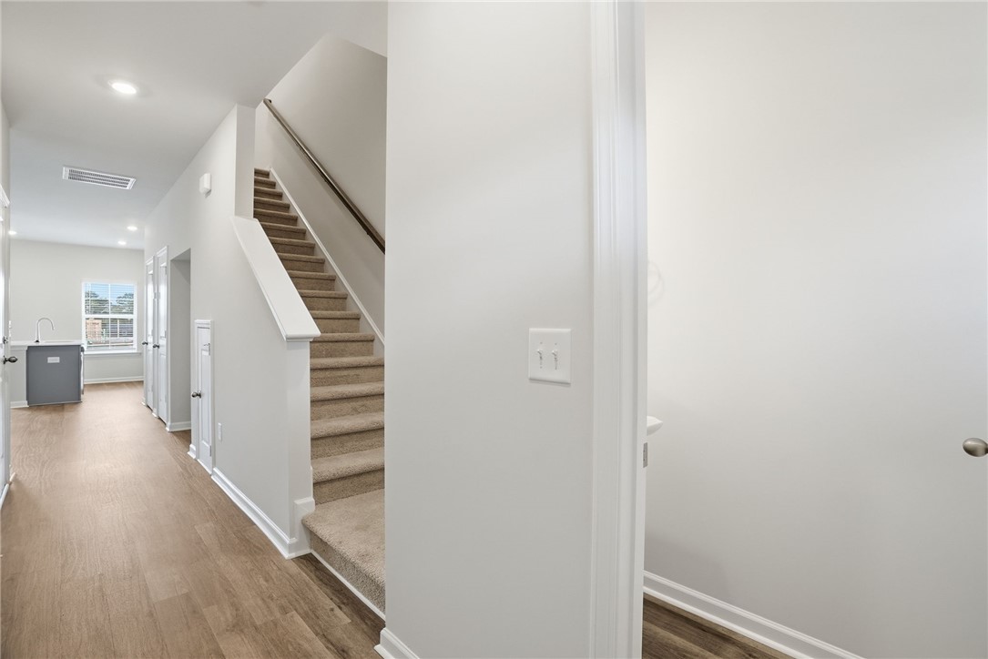 112 Lilac Loop Greenwood, SC 29649 - Photo 5 of 26 This interior hallway features warm flooring and a stairway with carpeted treads.
