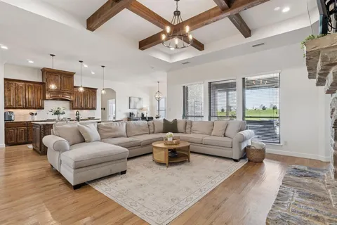 a living room with furniture kitchen view and a wooden floor