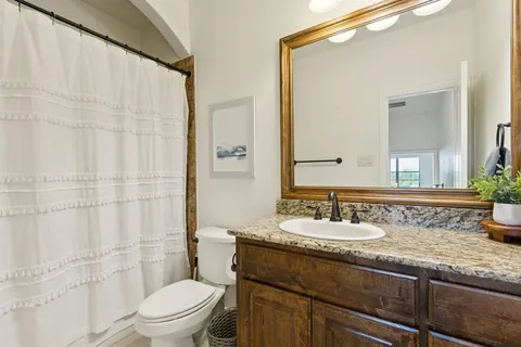 a bathroom with a granite countertop sink mirror vanity and toilet