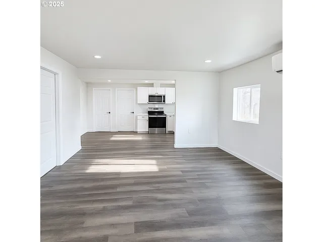 a view of kitchen and empty room with wooden floor