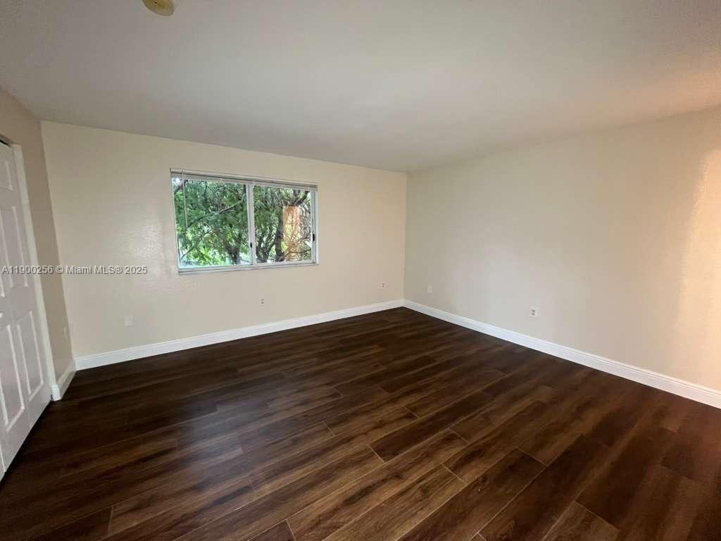 2271 Northwest 136th Terrace, Unit 2271 Opa-Locka, FL 33054 - Photo 17 of 23 a view of an empty room with wooden floor and a window