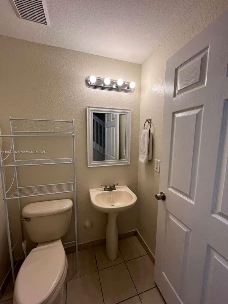 2271 Northwest 136th Terrace, Unit 2271 Opa-Locka, FL 33054 - Photo 4 of 23 a bathroom with a toilet sink and mirror