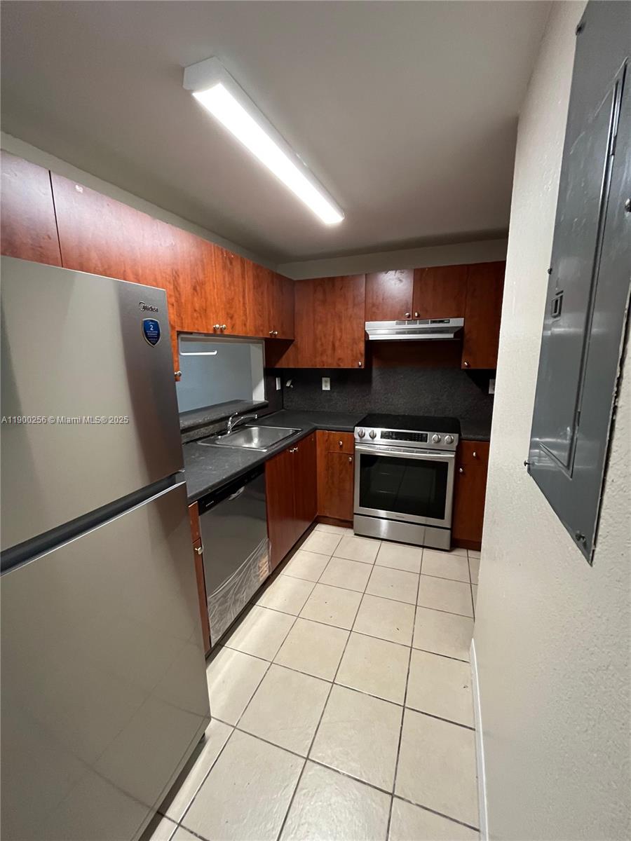 2271 Northwest 136th Terrace, Unit 2271 Opa-Locka, FL 33054 - Photo 9 of 23 a kitchen with granite countertop a refrigerator and a sink