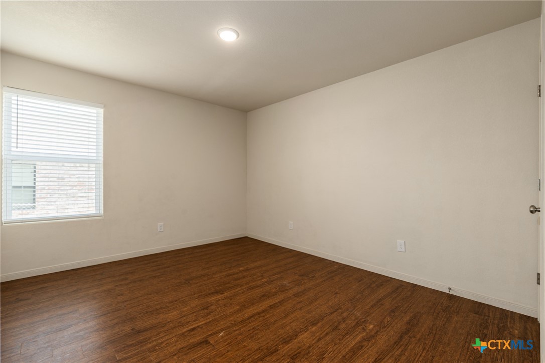 5701 Rustler Drive, Unit B Killeen, TX 76543 - Photo 12 of 29 an empty room with wooden floor and windows