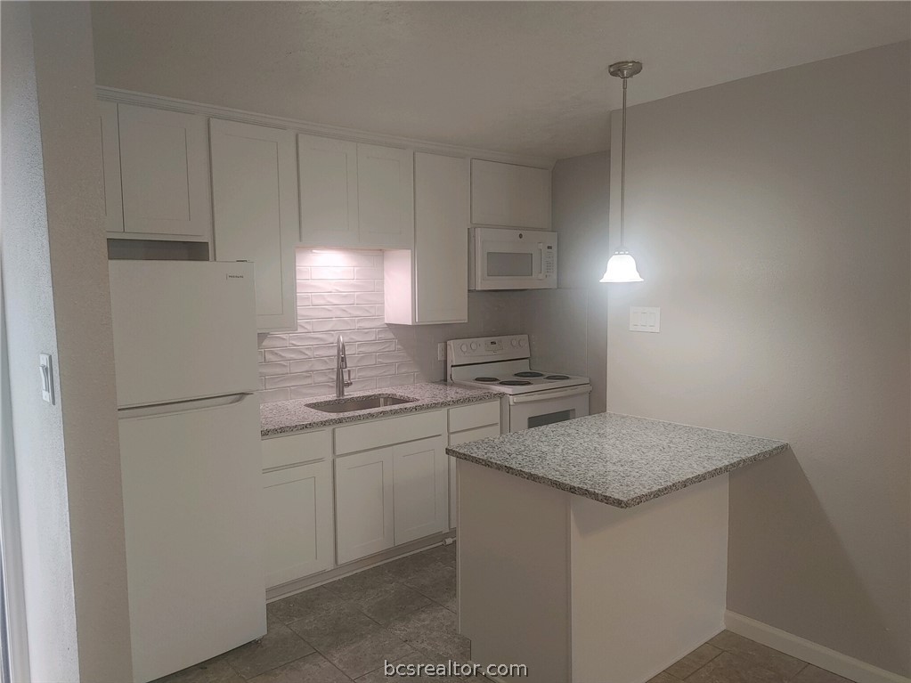 4212 Old College Road, Unit 3 Bryan, TX 77801 - Photo 1 of 9 a kitchen with a sink a stove a refrigerator and cabinets