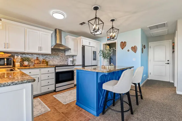 a kitchen with stainless steel appliances granite countertop a stove a sink dishwasher a dining table and chairs with wooden floor