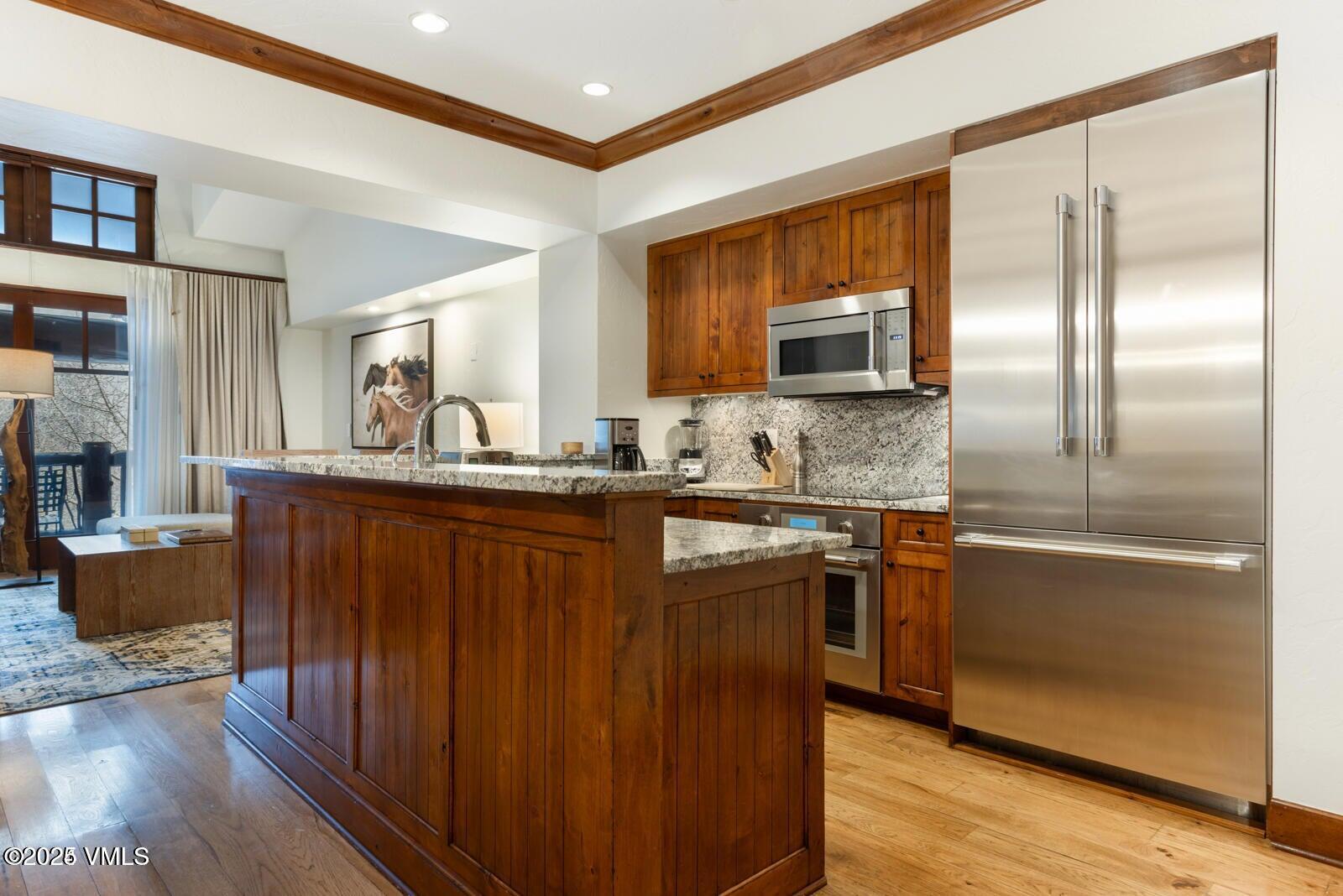 100 Bachelor Ridge Road, Unit 33146 Avon, CO 81620 - Photo 9 of 16 a kitchen with kitchen island granite countertop wooden cabinets a sink and stainless steel appliances