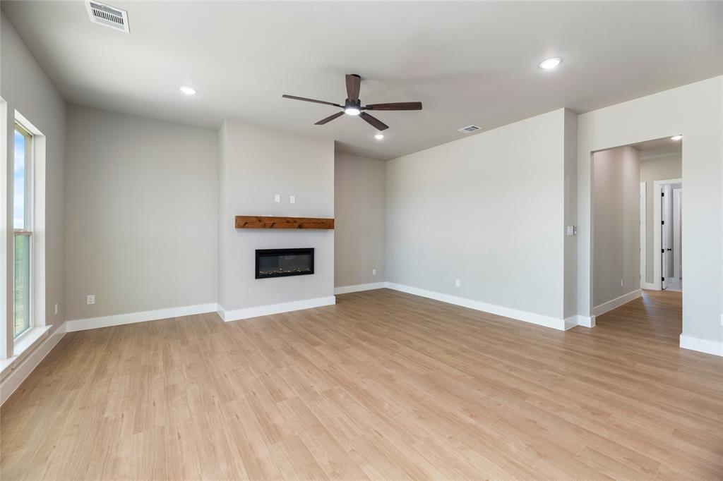 217 Fm 2258 Venus, TX 76084 - Photo 18 of 36 an empty room with wooden floor a ceiling fan and fireplace