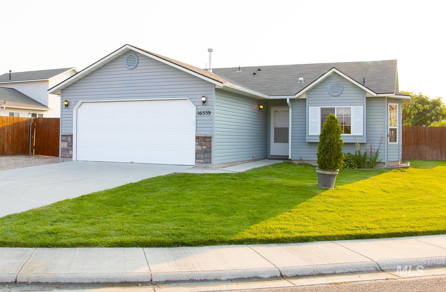 16559 Bayou Way Caldwell, ID 83607 - Photo 1 of 20 Single-story residence featuring light blue siding, a two-car garage with an overhead door, and stone accent details