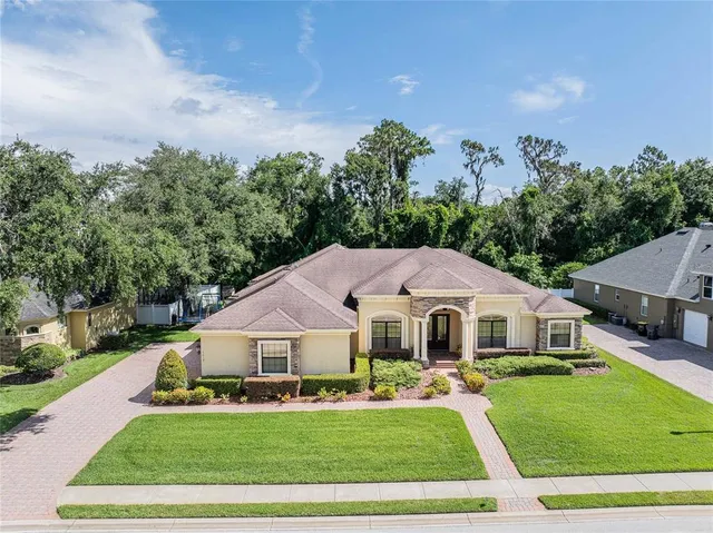 a aerial view of a white house sitting next to a yard with large trees