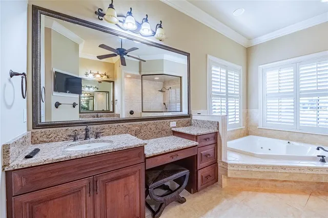 a bathroom with a granite countertop double vanity sink a large mirror a bathtub and window