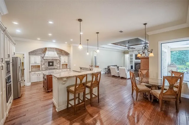 a open kitchen with stainless steel appliances granite countertop a stove top oven a refrigerator a dining table and chairs with wooden floor