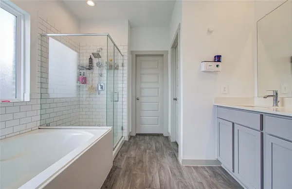 a bathroom with a tub shower sink vanity and a toilet