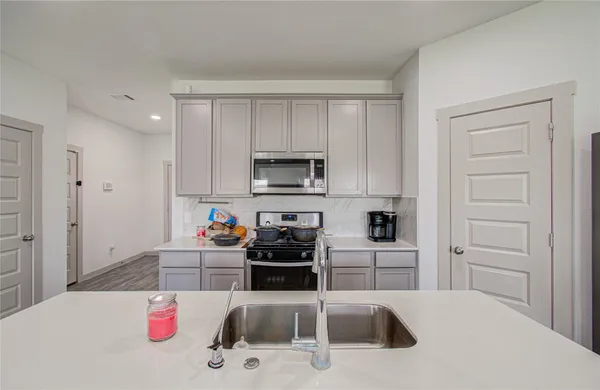 a kitchen with white cabinets and appliances