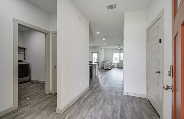 a view of a hallway with wooden floor a glass door and a bathroom