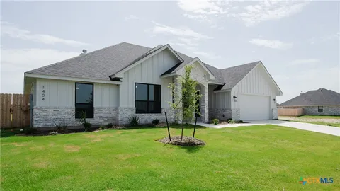 a front view of a house with a yard and tree