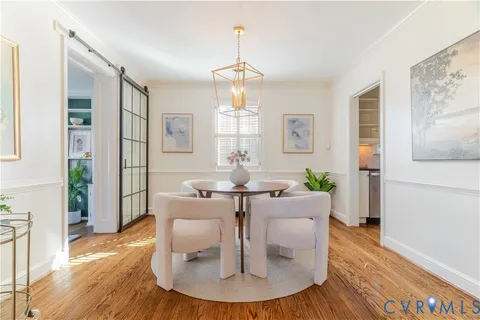 a dining room with wooden floor a chandelier a wooden table and chairs