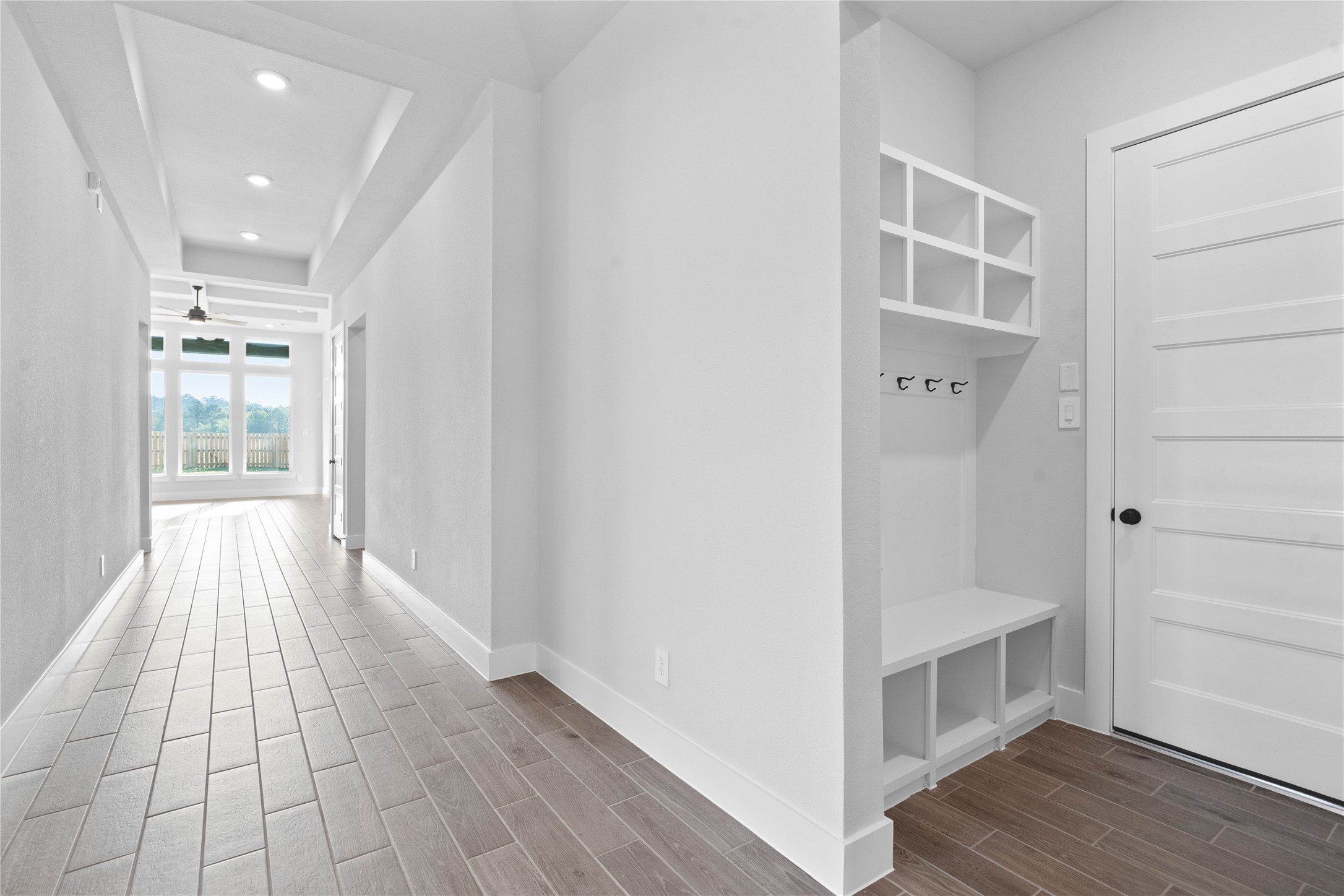 2114 Rowl Street Montgomery, TX 77316 - Photo 9 of 50 Step into this highly functional and stylish mudroom drop zone, an essential feature for a busy household. The space boasts custom-built white cabinetry and shelving, providing generous storage for coats, bags, and shoes. A comfortable built-in bench offers a convenient spot to sit, while three sleek hooks keep outerwear tidy and accessible.